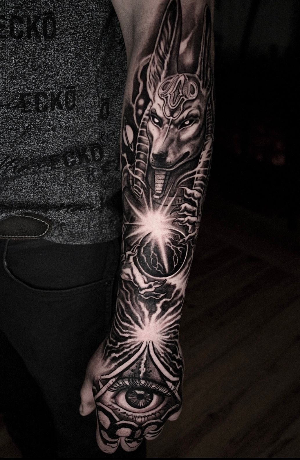 Arm tattoo of Anubis and Egyptian symbols; black and white. Artist Alexis Torres.