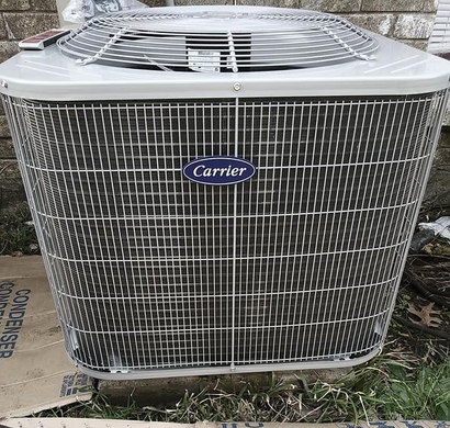 Carrier outdoor air conditioner unit with silver grille sitting on the ground outdoors