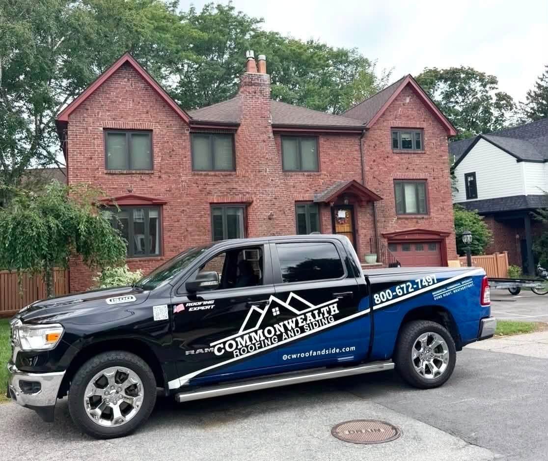 Black service pickup truck parked in front of a brick house with a garage.