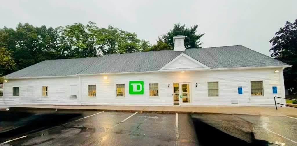 TD Bank storefront on a rainy day with white siding and green logo sign