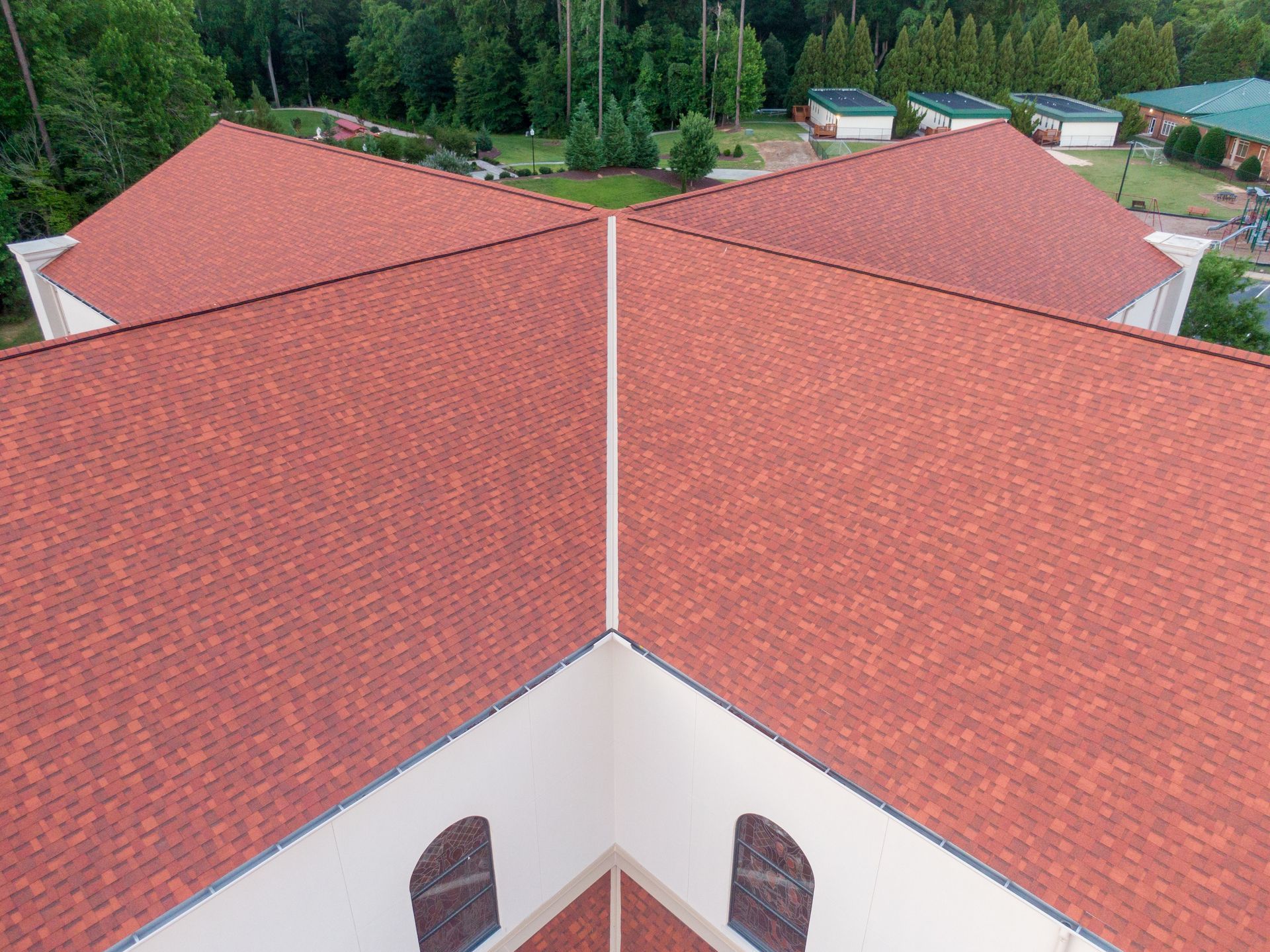 Aerial view of red-tiled rooftops on a building surrounded by trees