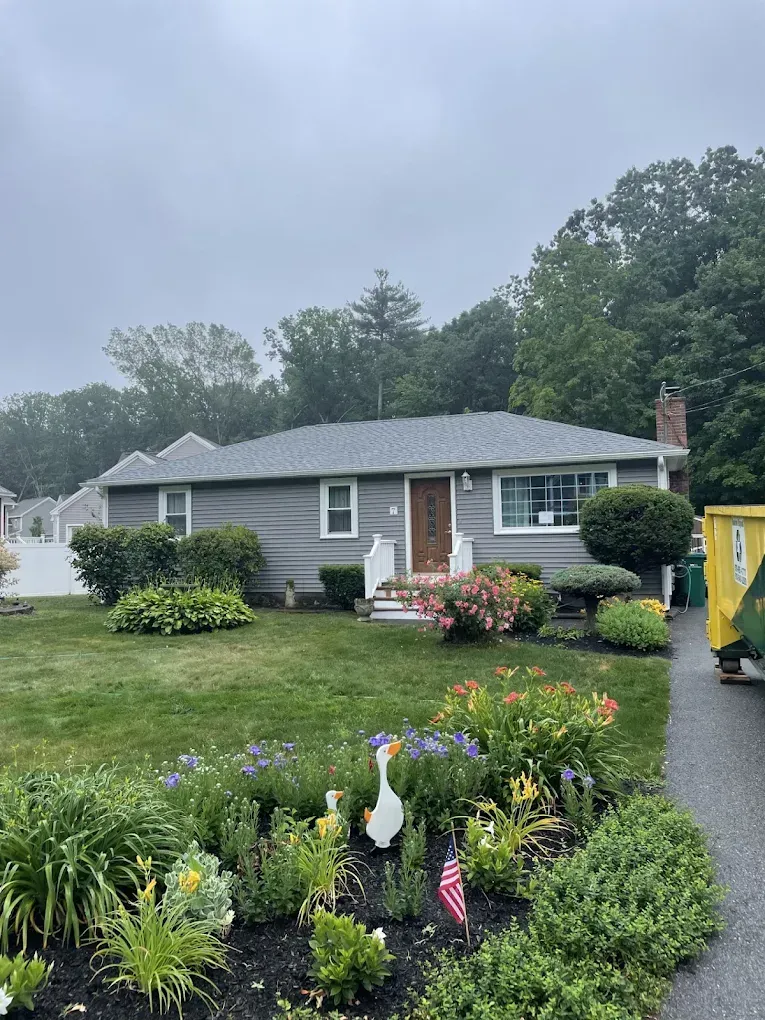 Single-story gray house with a landscaped front yard and garden flowers on a cloudy day