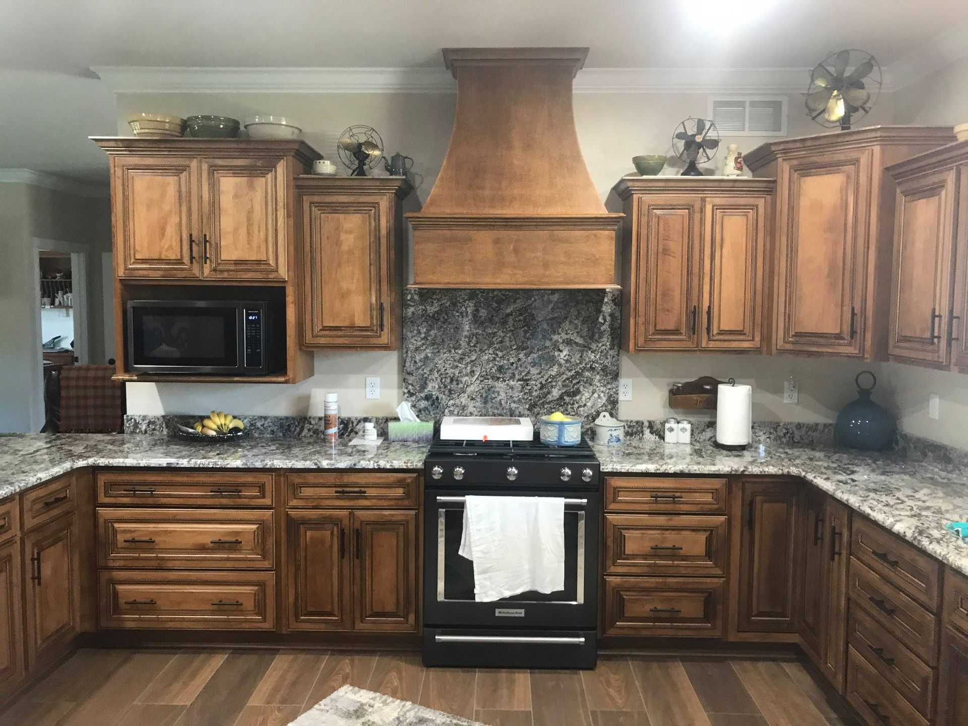 A kitchen with wooden cabinets , granite counter tops , a stove and a microwave.