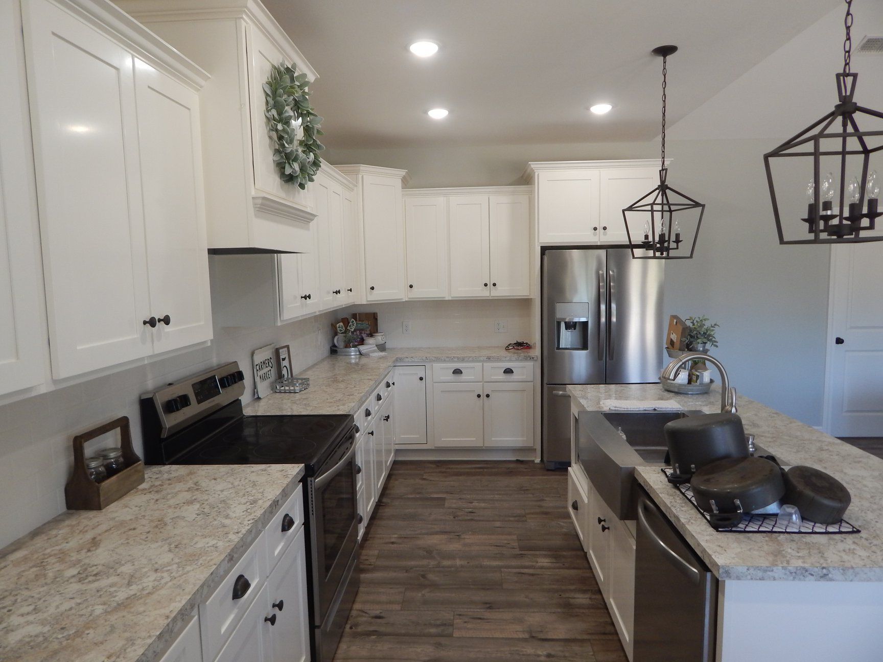A kitchen with white cabinets , stainless steel appliances , a sink , and a refrigerator.