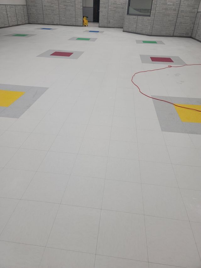 Empty white tiled room with colorful square floor markers and a faint red outline on the right.