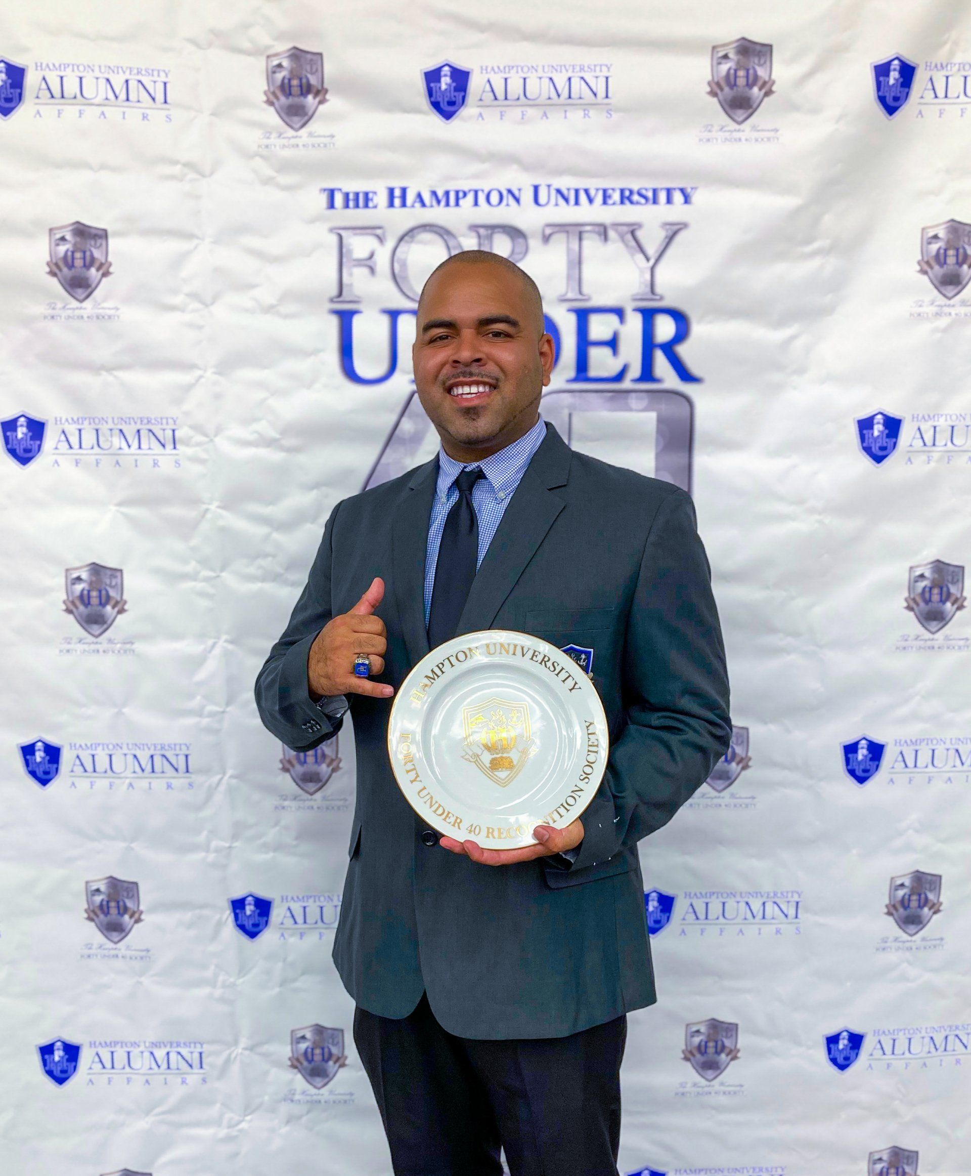 A man in a suit and tie is holding a plate and giving a thumbs up.