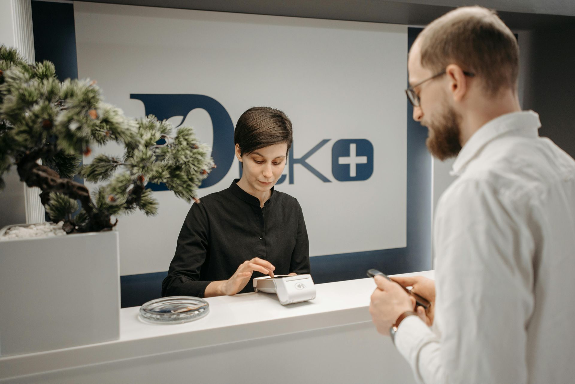 A man is talking to a woman at a counter in a hospital.