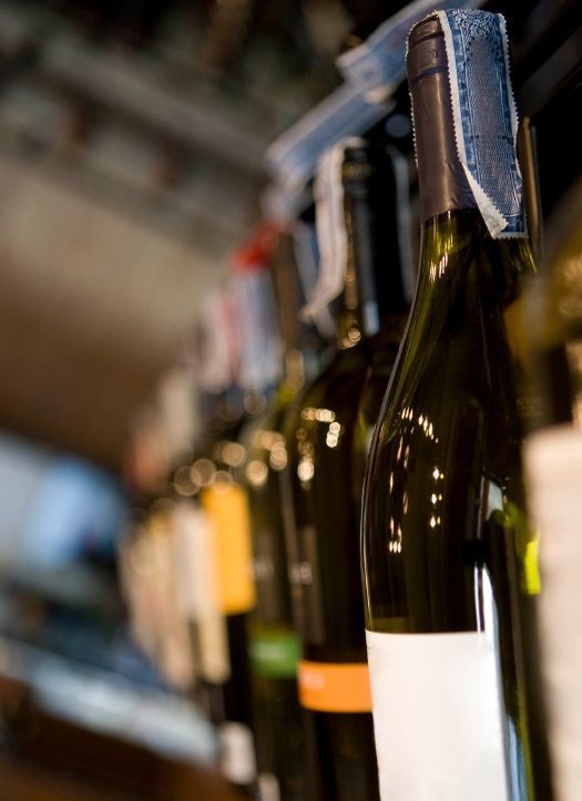 Botellas de vino alineadas en el estante de una tienda con etiquetas en blanco, en un enfoque selectivo y borroso.