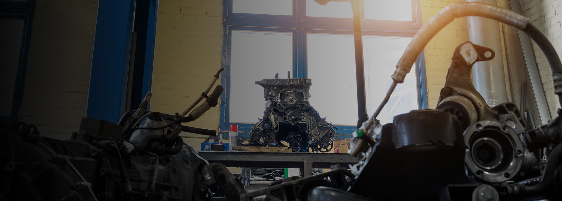 A mechanical creature sits on a table in a workshop, surrounded by car parts. | Doran-King Garage Inc