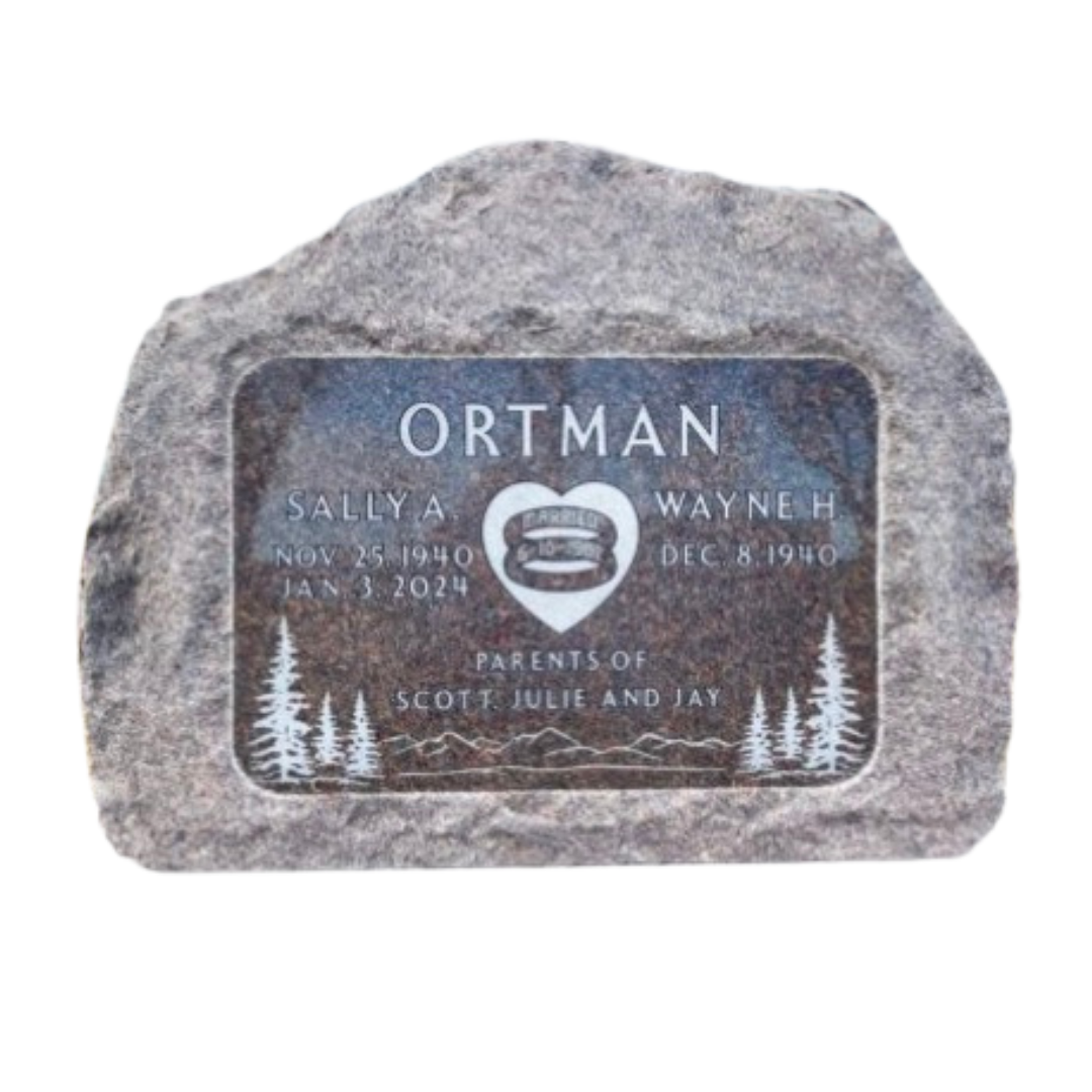 Companion marker engraved into a large stone, featuring trees, a heart, and wedding rings,