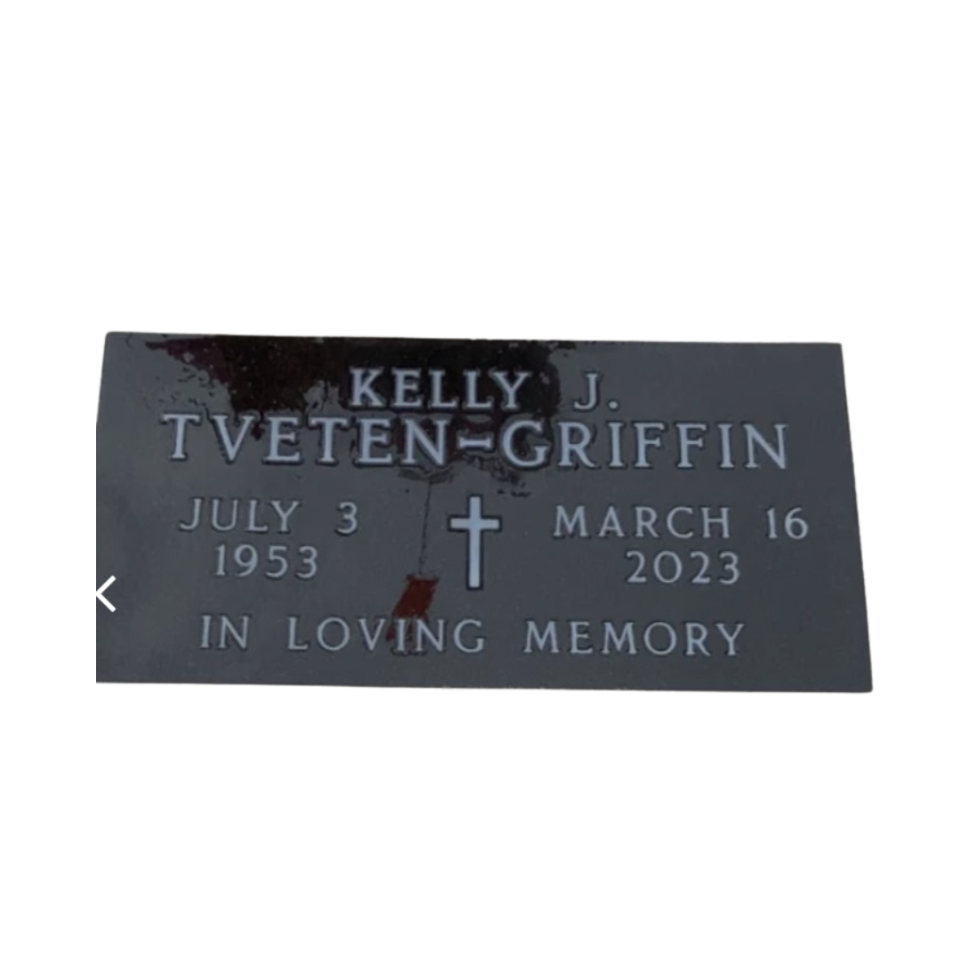 Flat, black granite marker with a cross in the middle.