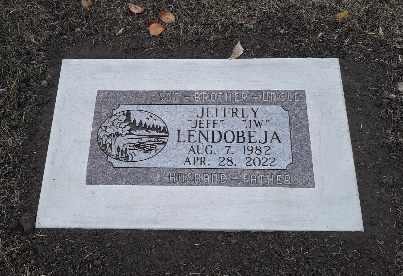 Flat marker engraved with the name Jeffrey Lendobeja, made from a slab of granite and set directly into the ground.