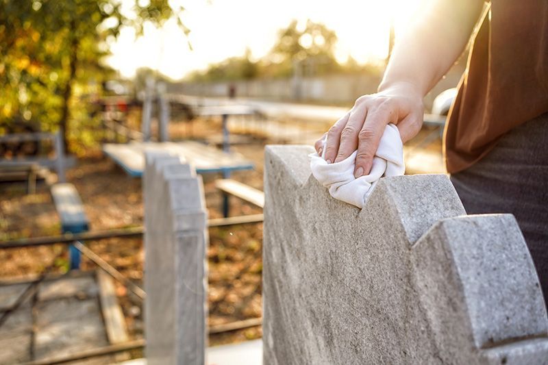 A man cleaning a headstone with a soft cloth.