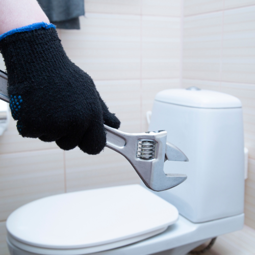 a person is fixing a toilet with a wrench