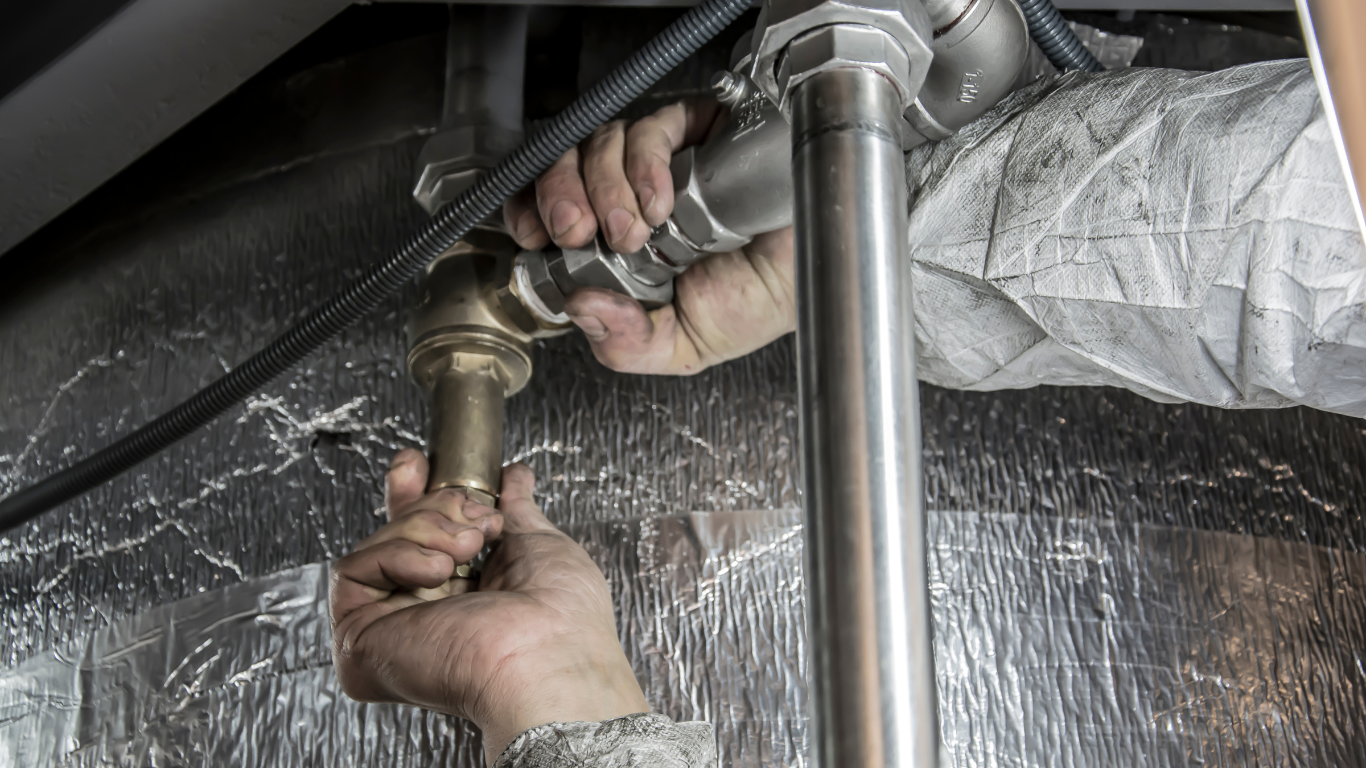 a plumber is fixing a sink pipe with a wrench .