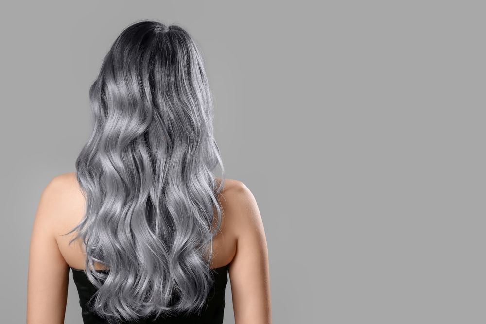 Long wavy silver hair seen from behind against a gray background