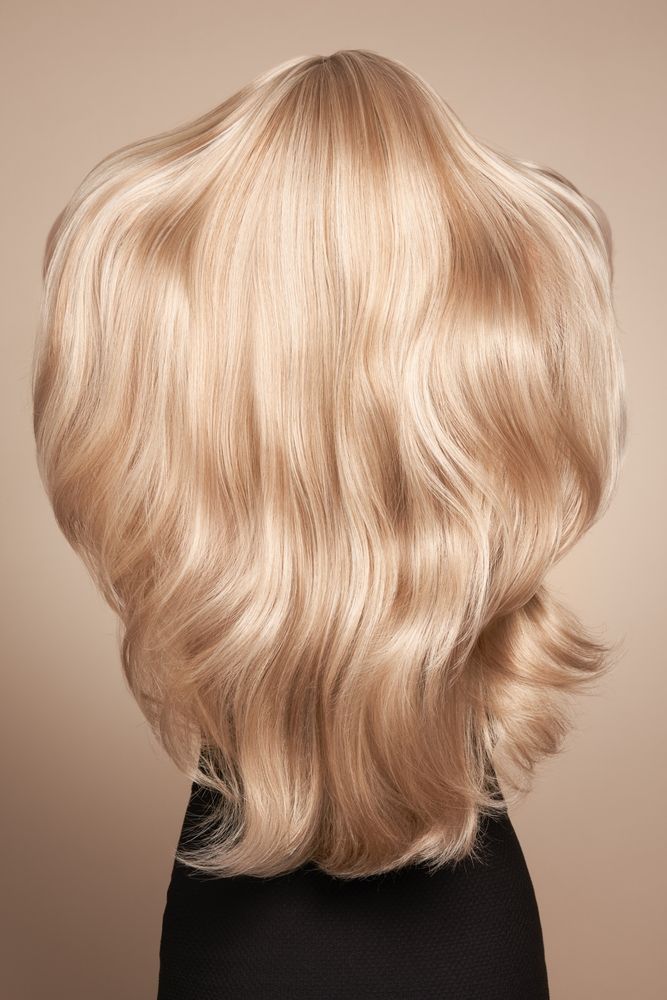 Blonde wavy layered hair on a mannequin against a beige background