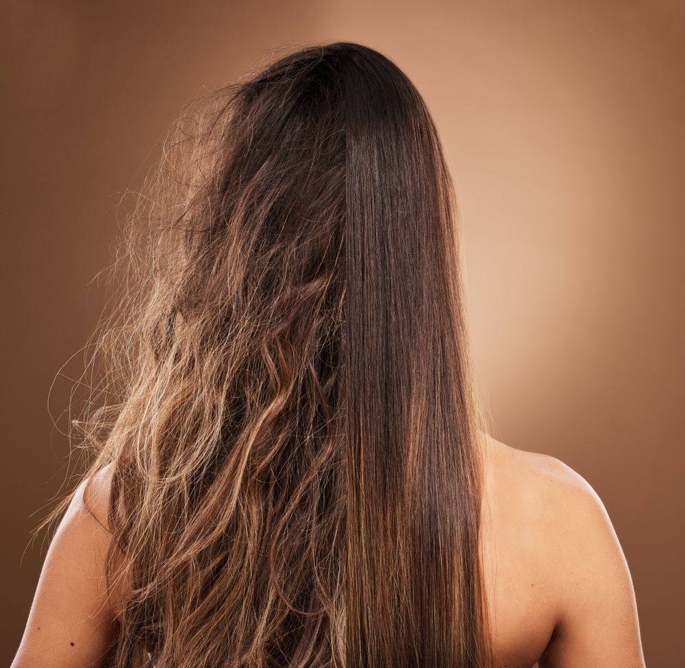Back view of a person with long brown hair against a plain tan background