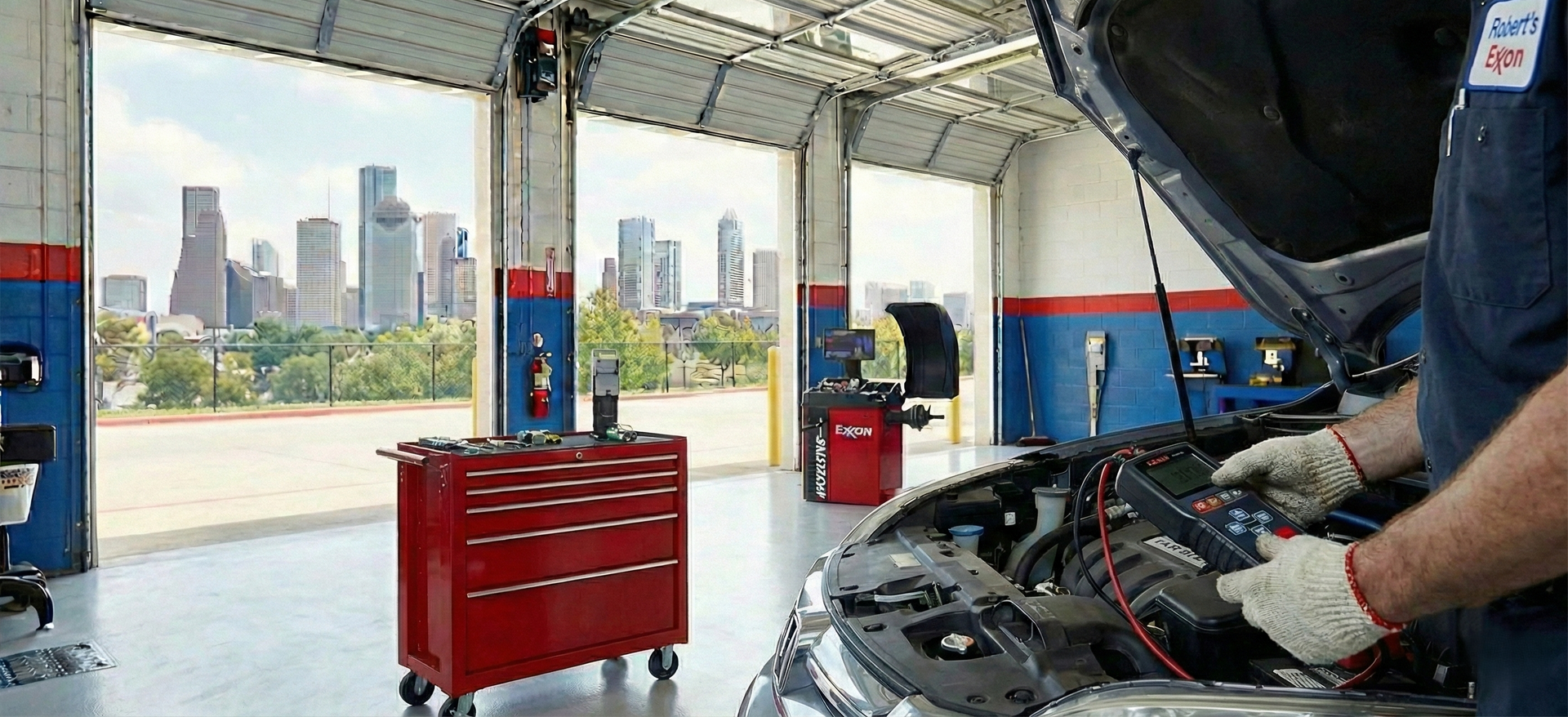 Mechanic working on a car in a garage with a city skyline view.