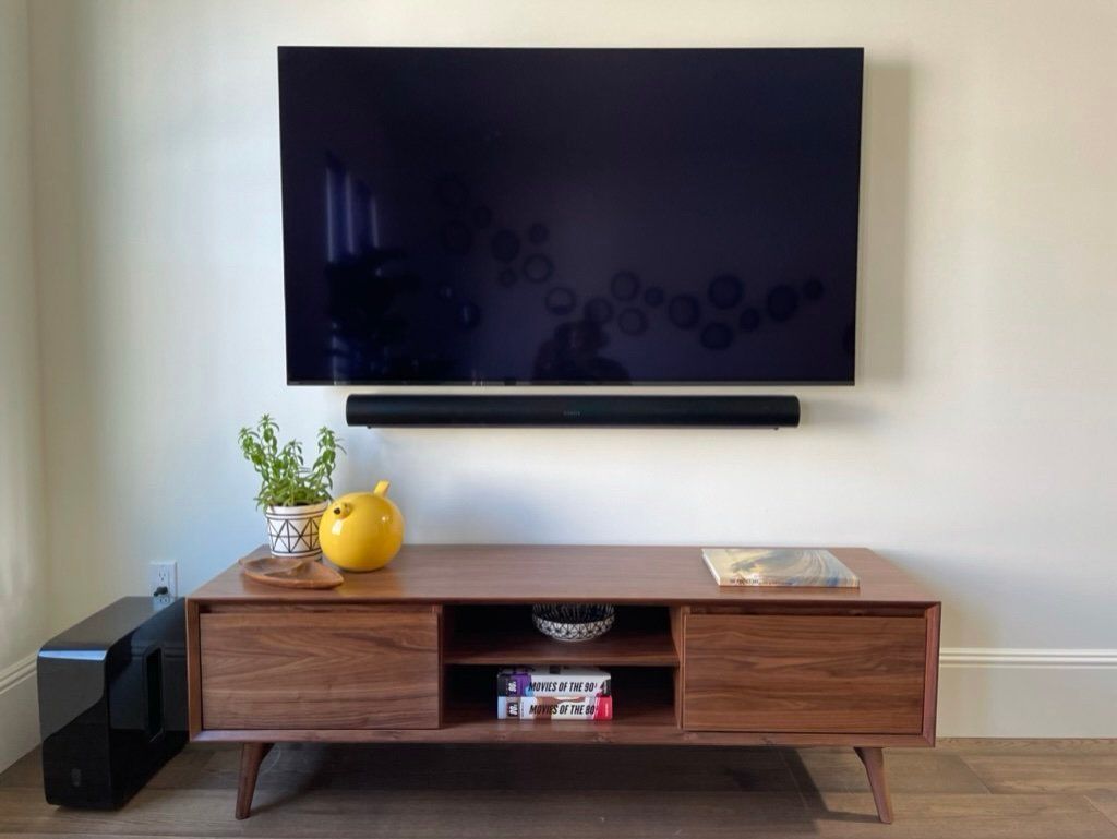 A flat screen tv is mounted on a wall above a wooden entertainment center
