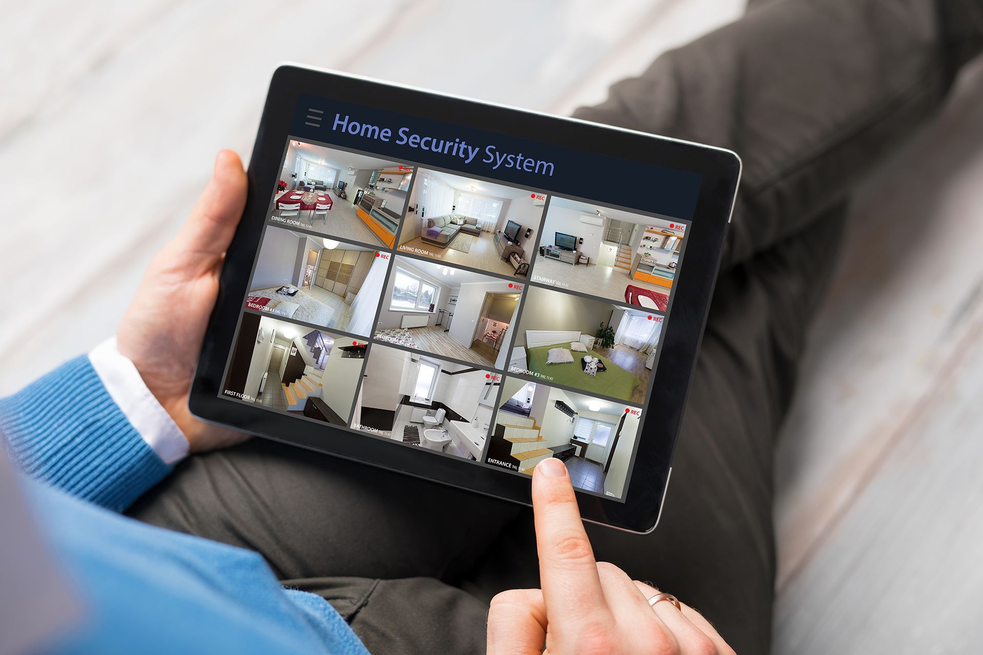 A person is holding a tablet with a home security system on it