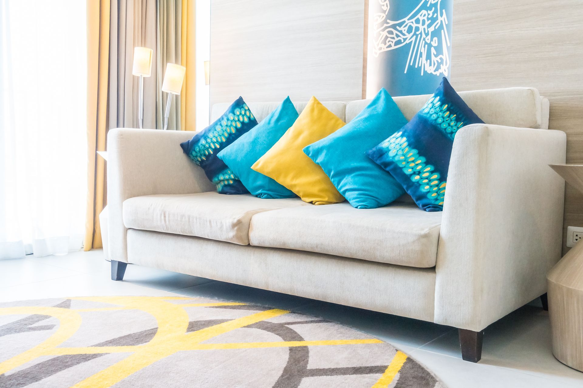 Three blue industrial fans dry a beige carpet in a living room near a fireplace.