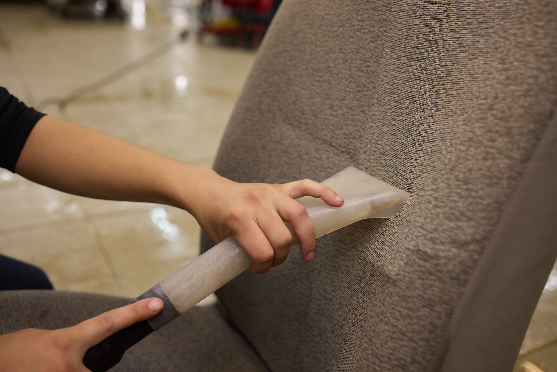 A dryer vent brush removing a large, dense clump of gray lint from a white wall corner.