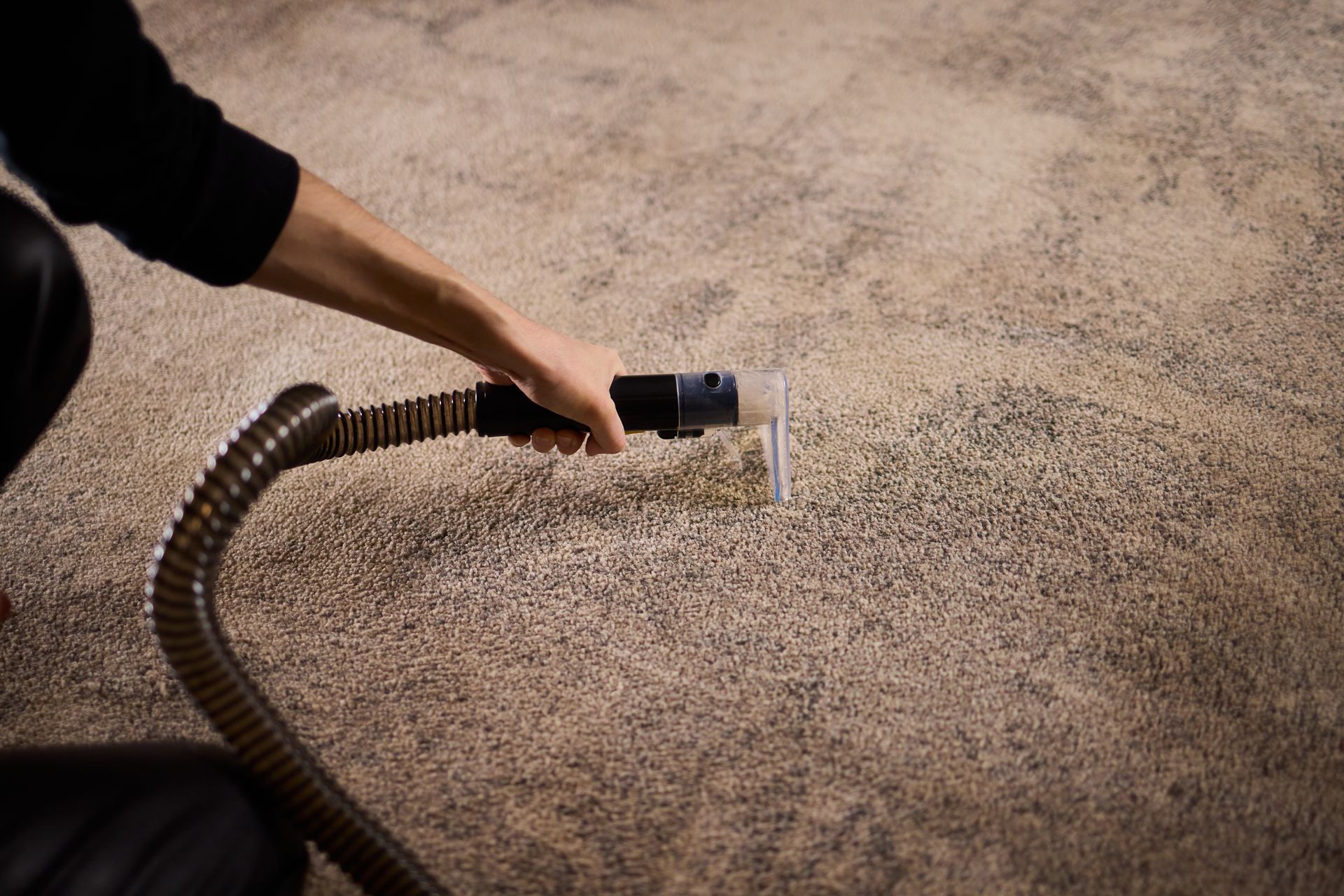 Three blue industrial fans dry a beige carpet in a living room near a fireplace.