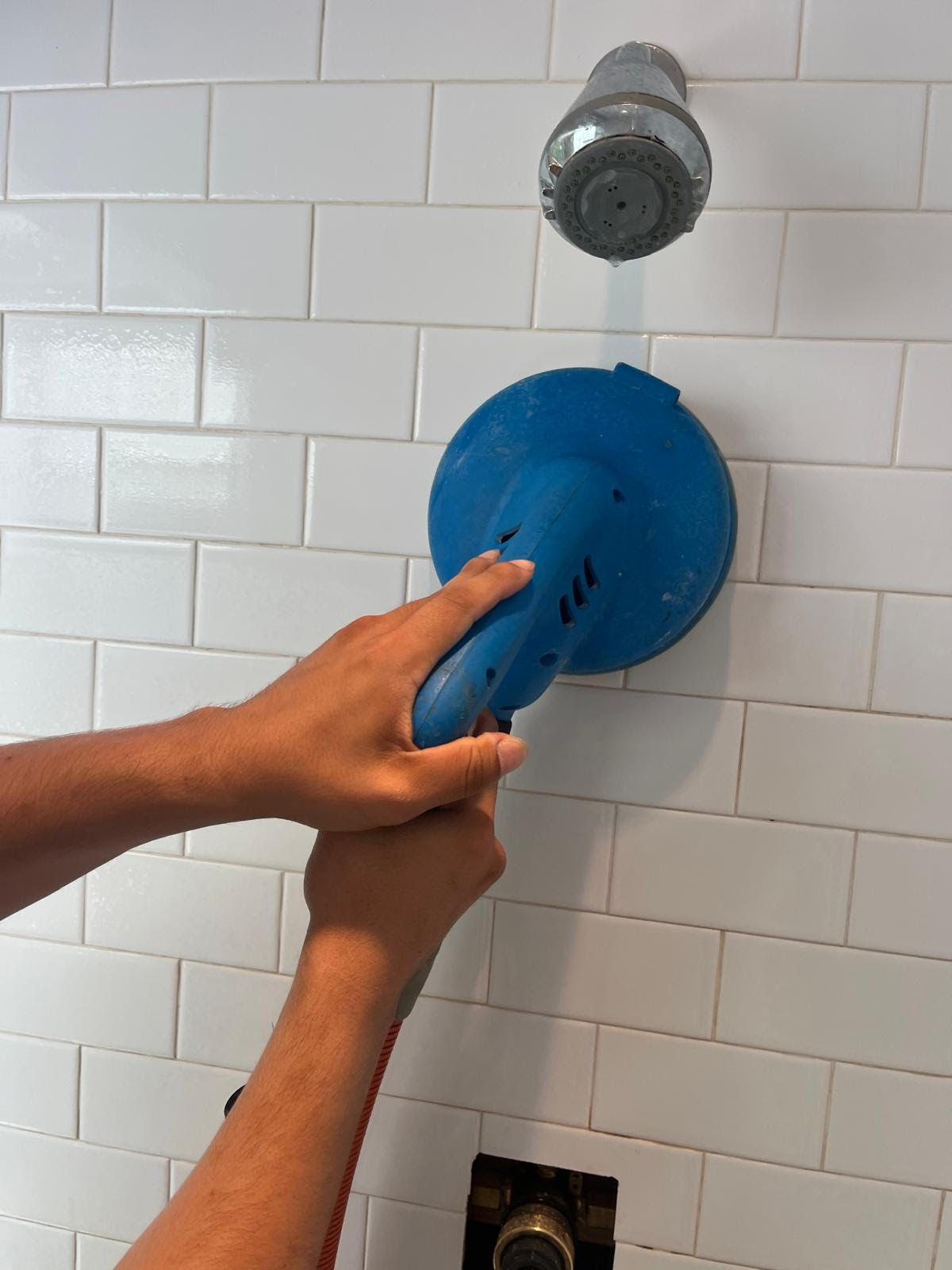 A dryer vent brush removing a large, dense clump of gray lint from a white wall corner.