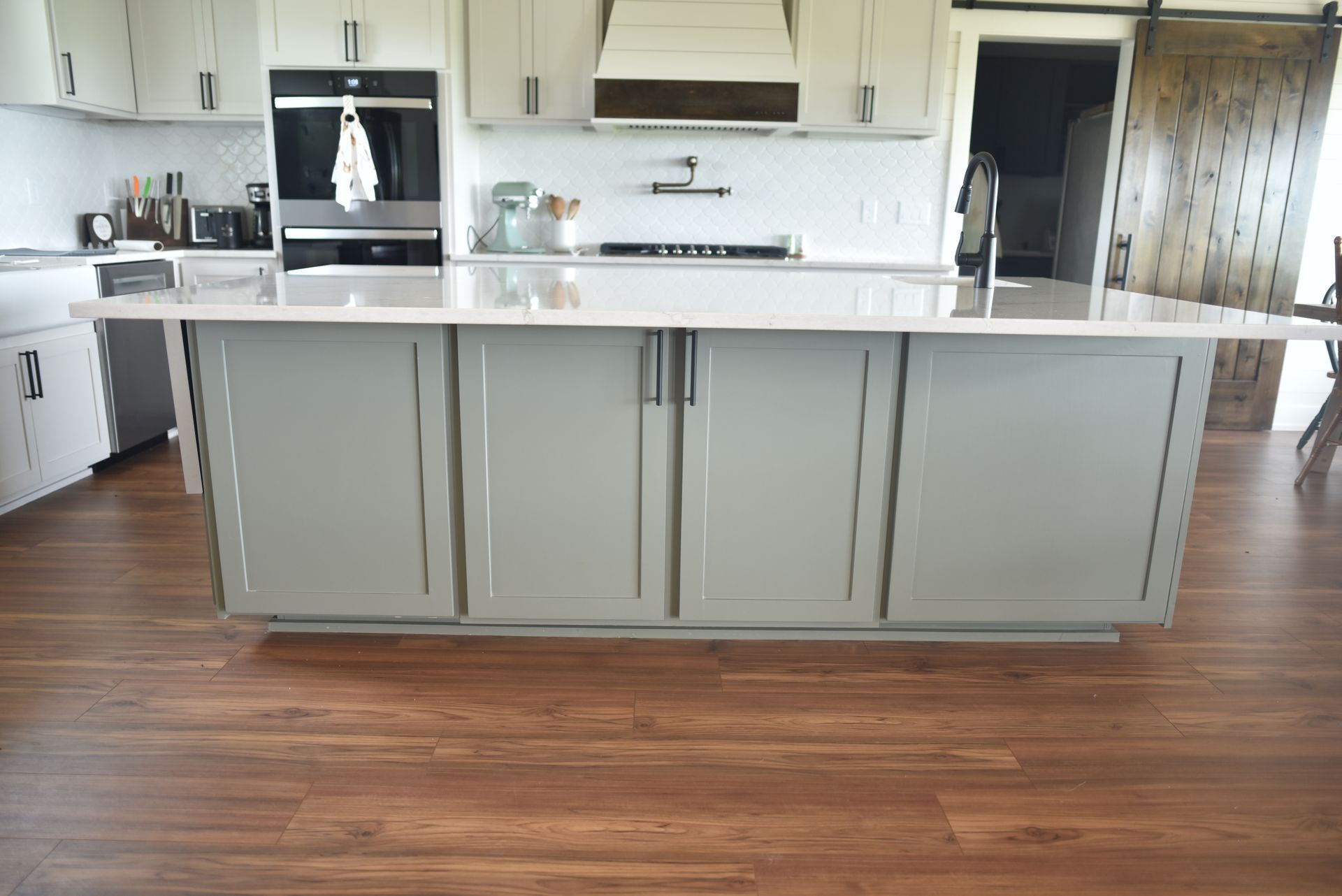 Modern kitchen with gray island cabinets, white countertops, and wood flooring