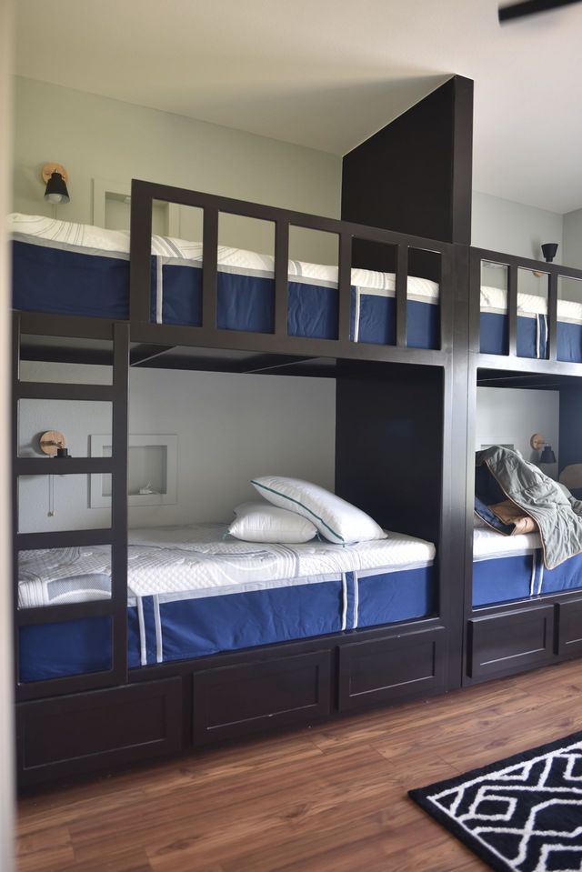 Dark wood bunk beds with blue and white bedding in a bedroom with hardwood floors.