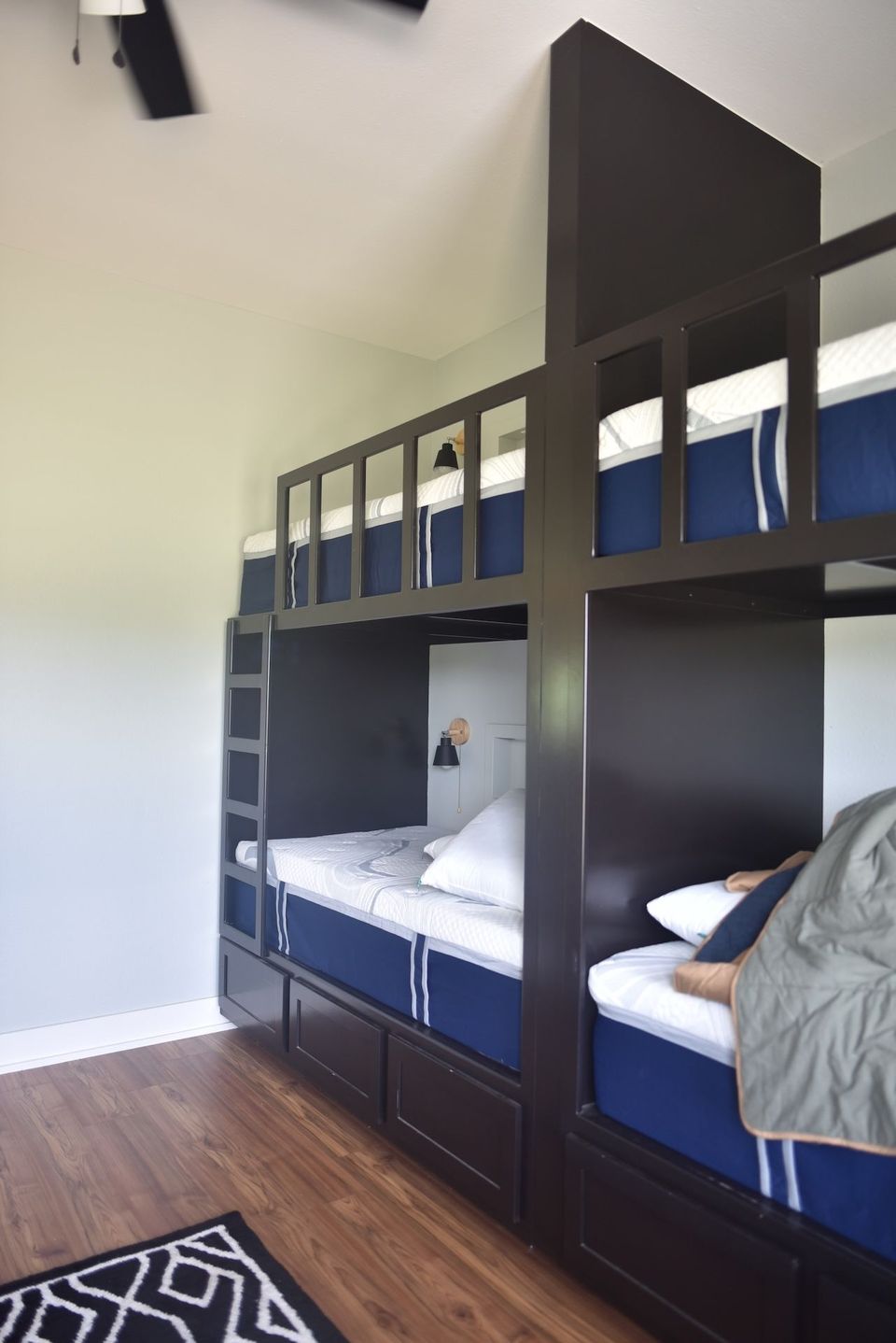 Dark wood bunk bed with blue bedding in a bright room with hardwood floors