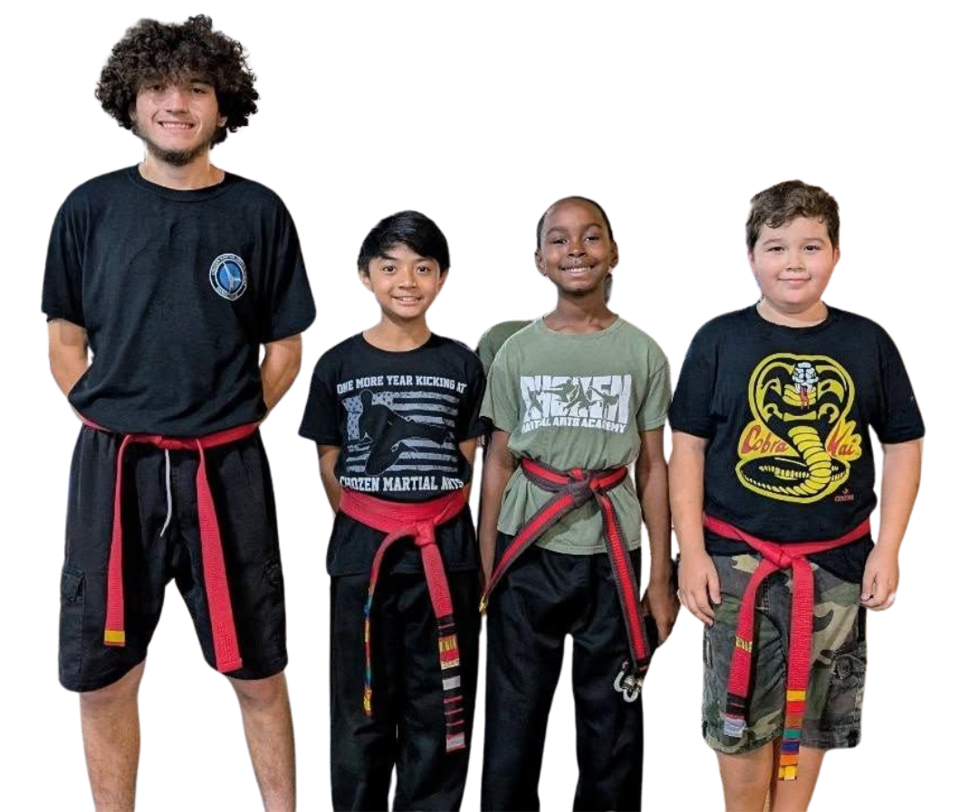 A group of kids in karate uniforms are sitting on the floor drinking water