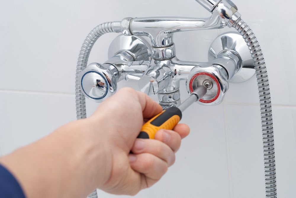 A Person Is Fixing A Shower Head With A Screwdriver — H2O Plumbing & Maintenance Services In Armidale, NSW