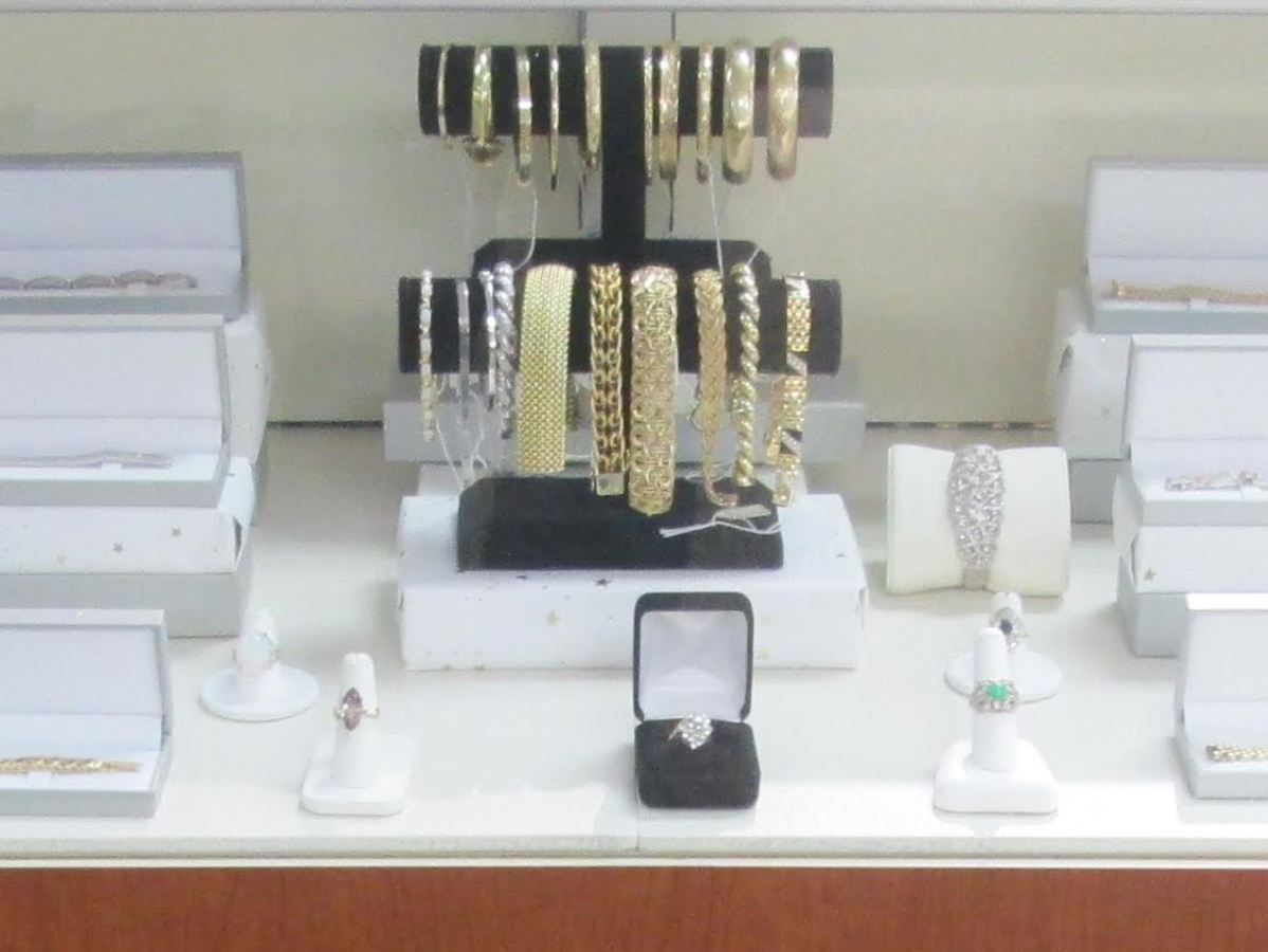 Jewelry display case with gold and silver bracelets, rings, and a ring box.