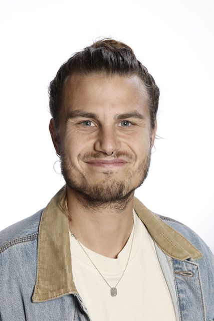 En mand med en knold på hovedet har en brun jakke på.