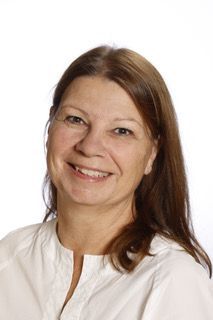 En kvinde i en hvid skjorte smiler til kameraet.