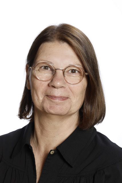 En kvinde i en hvid skjorte smiler til kameraet.
