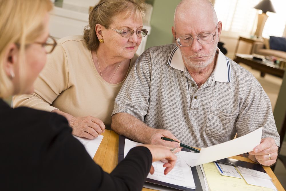 A Man is Talking to an Elderly Couple in a Kitchen — Pollock Ingram Solicitors in Caloundra, QLD