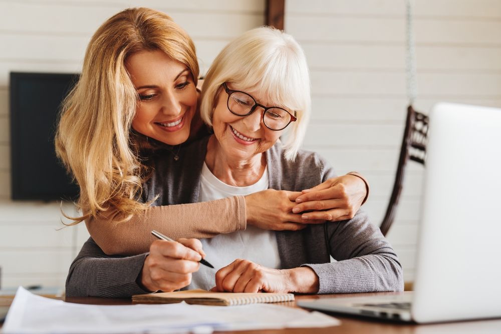 Two Women Hugging and Filling Out a Document — Pollock Ingram Solicitors in Caloundra, QLD