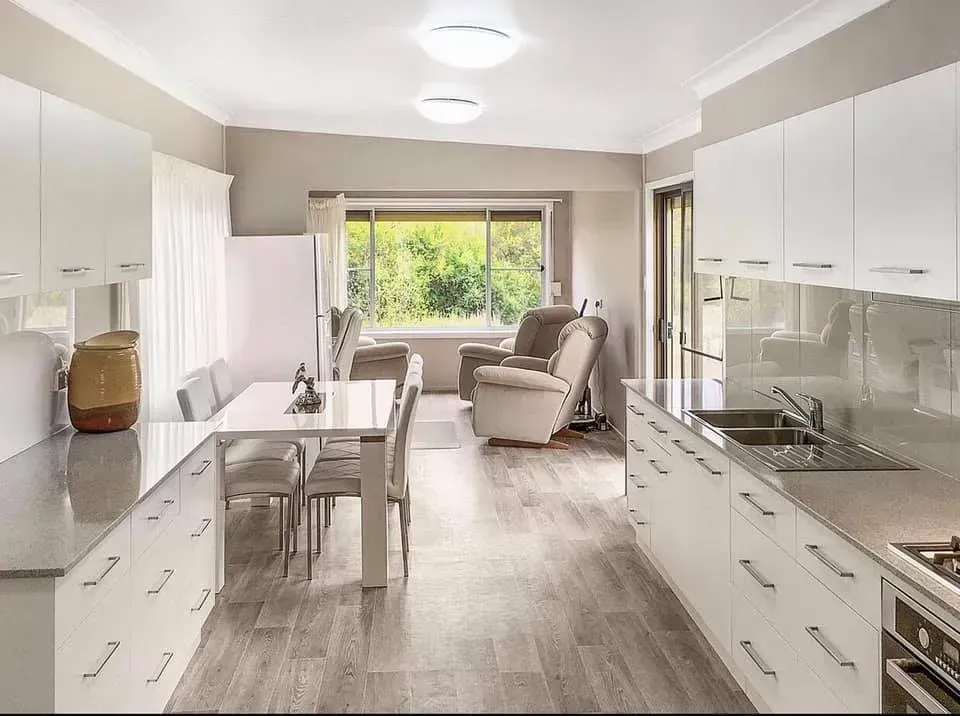 A Kitchen With White Cabinets, a Sink, a Table and Chairs — Moore Than Just Kitchens In Manilla, NSW