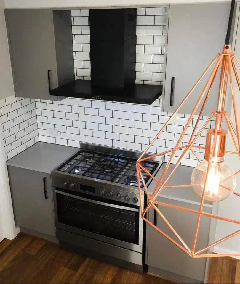 A Kitchen With a Stove and a Light Hanging From the Ceiling — Moore Than Just Kitchens In Manilla, NSW