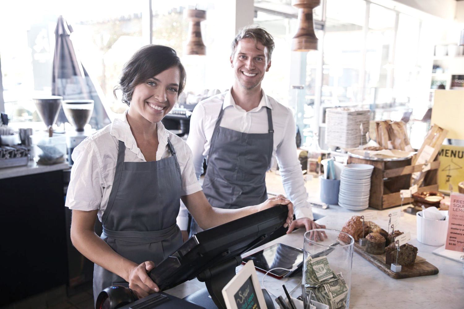 A man and a woman are standing next to each other in a restaurant.