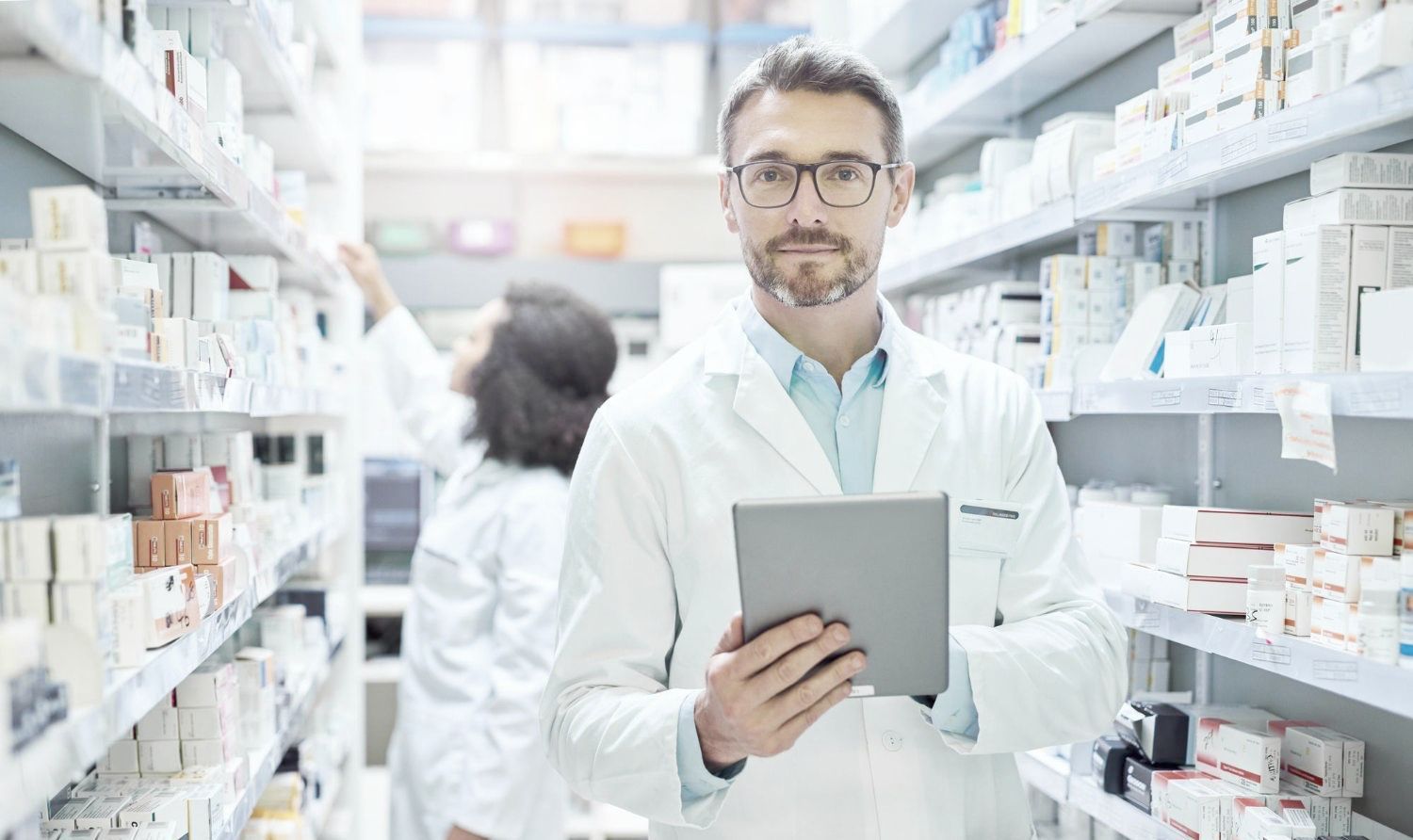 A pharmacist is holding a tablet in a pharmacy.