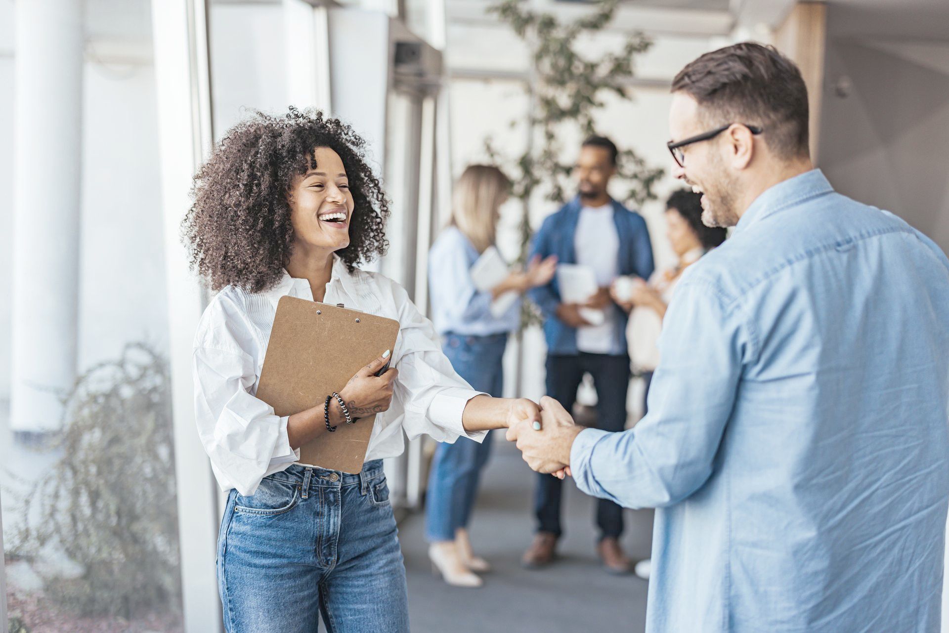 A man and a woman are shaking hands in an office.