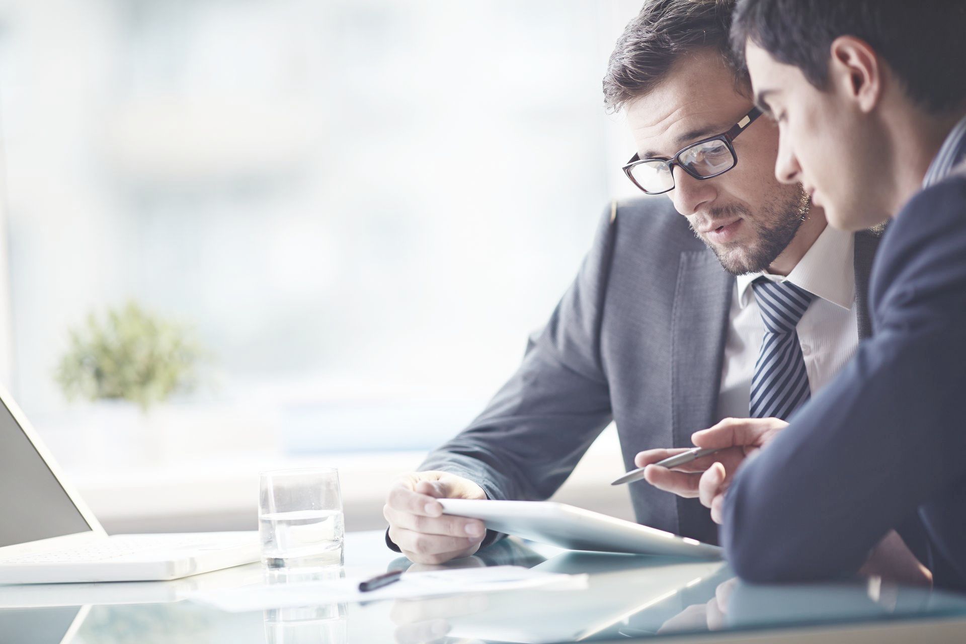 Two men are sitting at a table looking at a piece of paper.