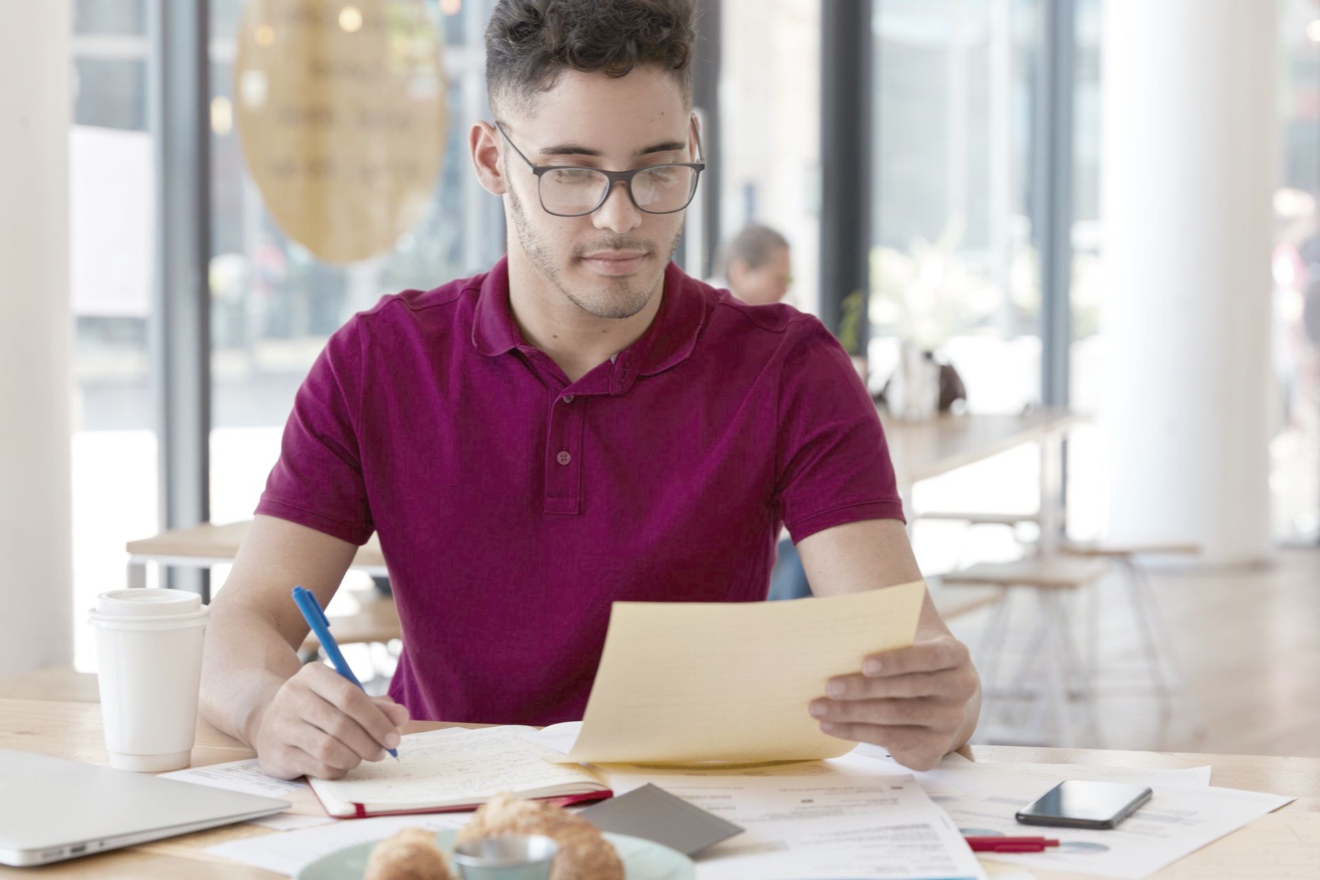 A man is sitting at a table writing on a piece of paper.