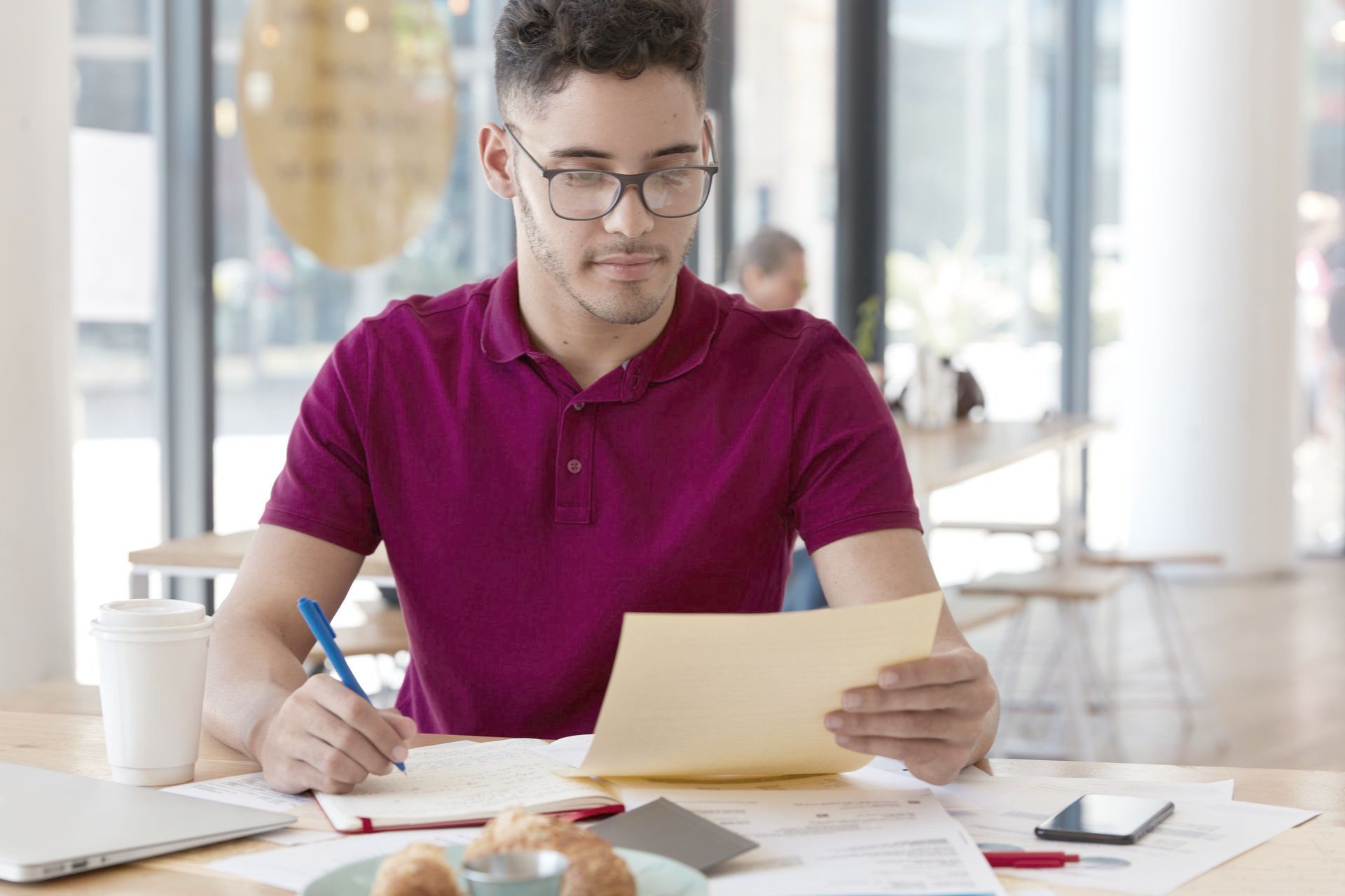 A man is sitting at a table looking at a piece of paper.