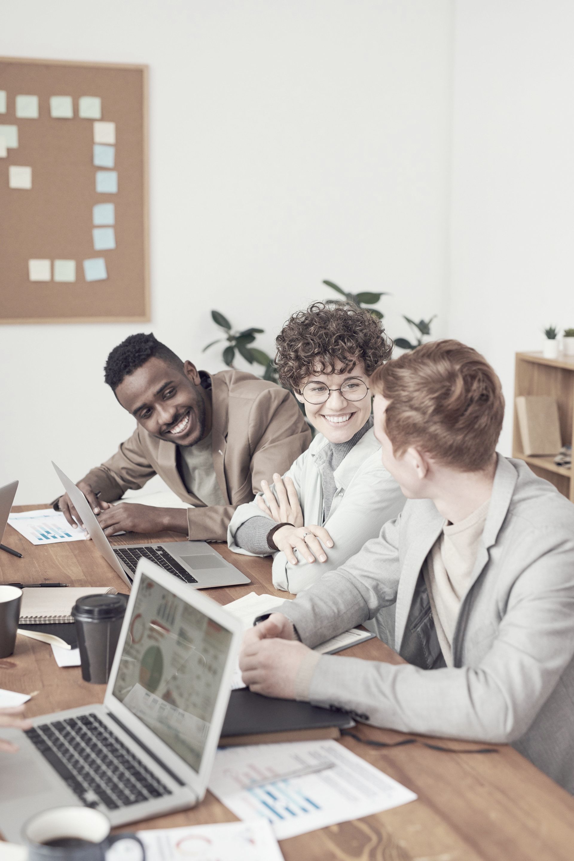 A group of people are sitting at a table with laptops.