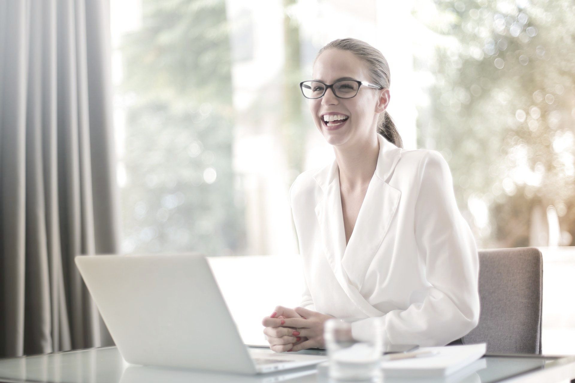 A woman is sitting at a desk in front of a laptop computer.